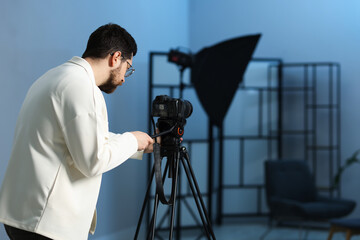 Man with professional video camera in studio, space for text