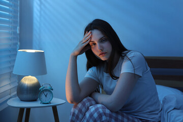 Frustrated young woman suffering from insomnia on bed indoors