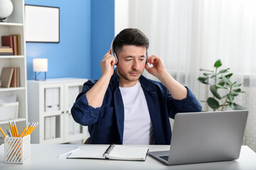 Man learning online using laptop at desk indoors. Self-study