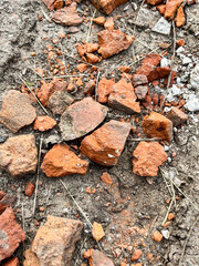 Broken red bricks scattered on dry soil, construction debris symbolizing demolition, waste, and urban development processes