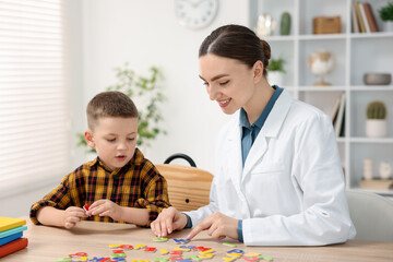Dyslexia treatment. Pediatrician working with little boy at table indoors