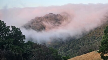 Blanket of fog rolling over a mountain ridge at sunrise