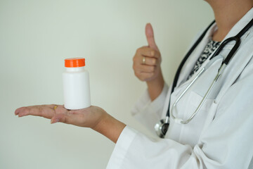 An asian young doctor with stethoscope is holding an medicine bottle to assess the quality of...