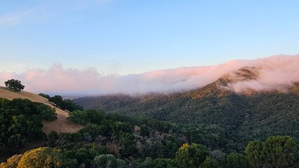 Blanket of fog rolling over a mountain ridge at sunrise