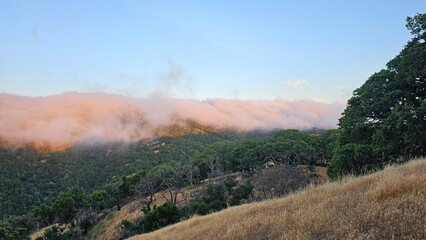 Blanket of fog rolling over a mountain ridge at sunrise