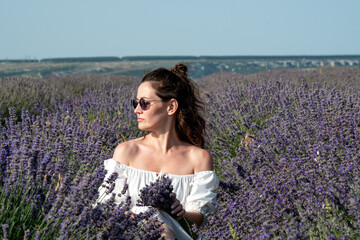 Beautiful woman at purple lavender field with violet blossom lavanda flowers. French young girl in provence lavender farm wears white dress.