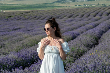 Beautiful woman at purple lavender field with violet blossom lavanda flowers. French young girl in provence lavender farm wears white dress.