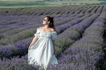 Beautiful woman at purple lavender field with violet blossom lavanda flowers. French young girl in provence lavender farm wears white dress.