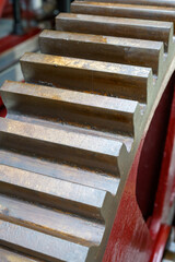 Close-up of a large metal geared wheel in a steam powered factory setting.