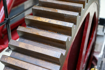 Close-up of a large metal geared cog wheel in a steam powered factory setting.