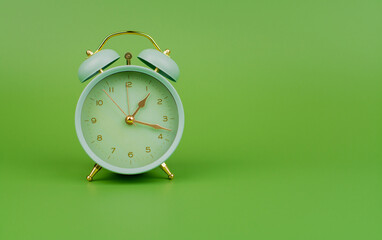 Green alarm clock photo in studio on green background. Time and work and life.
