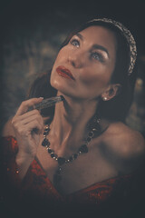 Pretty woman in red apparel making rituals in dark forest