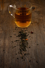 a clear glass mug of green tea, centered on a rustic wooden surface with scattered tea leaves, evokes a sense of calm and natural purity. Ideal for wellness, mindful living, or beverage themes