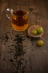  a glass of green tea, loose tea leaves, and fresh green grapes on rustic wood, evoking a sense of natural wellness and delightful simplicity. Ideal for health blogs, beverage industry content
