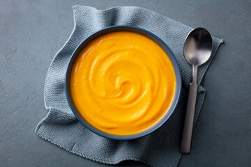 Pumpkin traditional soup with creamy silky texture. Grey background. Close up. Top view.