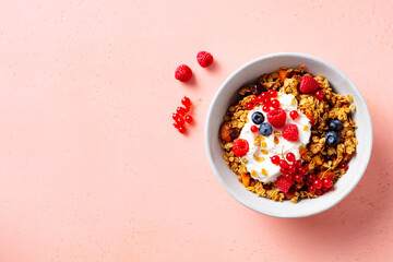 Healthy breakfast. Granola, muesli with yogurt and fresh berries. Pink background. Copy space. Top view.