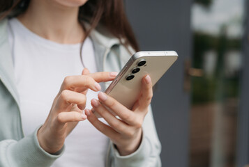 Close-up of hands holding and using a modern smartphone outdoors, showcasing technology and connectivity in daily life 