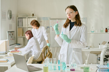 Scientists in lab coats conducting experiments with various chemical substances in modern...