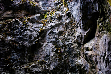 The rough, uneven walls of the cave made of marble-limestone close into a corner. It is illuminated from above by natural diffused light through an artificial crevice.