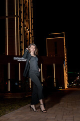 A girl in a night city, a beautiful young girl walks through the night city in an evening dress and heels