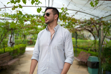 Handsome man entrepreneur checking quality of grape in organic vineyard.