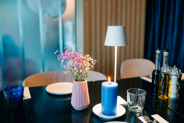 Elegant dinner table setting with flowers, candles, and decorative items in a cozy restaurant atmosphere