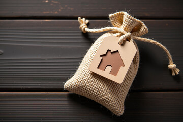A small burlap bag with a house tag sits comfortably on a dark wooden background.