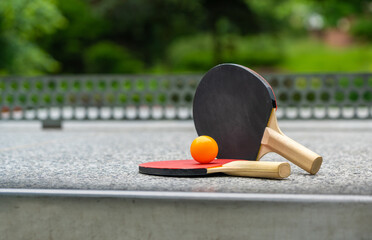 Rackets for table tennis in park close up. Red black ping pong table tennis paddles and yellow ball