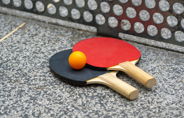 Rackets for table tennis in park close up. Red black ping pong table tennis paddles and yellow ball