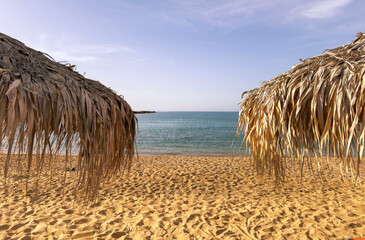Straw umbrellas on a sandy beach, close up. Sunny day at sea. Summer holiday
