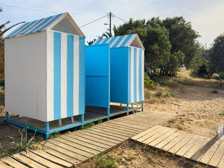 Beach cabins on sand. Small huts with blue stripes, sandy beach in Crete island