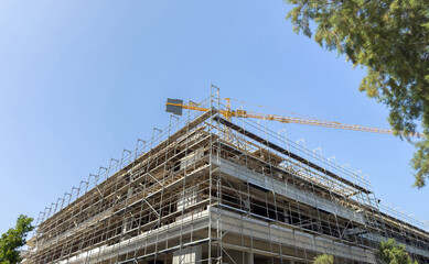 Building construction site, scaffolding system and tower crane, under construction project