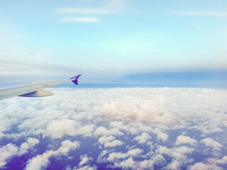 Plane flying over clouds, aerial view from airplane window, fluffy cloudscape and blue sky