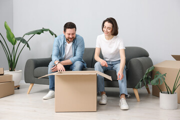Moving day. Happy couple unpacking their belongings in new home