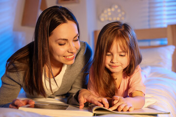 Smiling mother reading bedtime story to her daughter at home