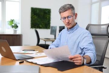 Naklejka premium Businessman doing paperwork at table in office