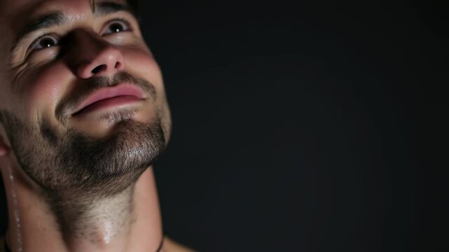 A close-up portrait of a man with a sweaty face and neck, suggesting exertion or heat, is captured against a dark backdrop.