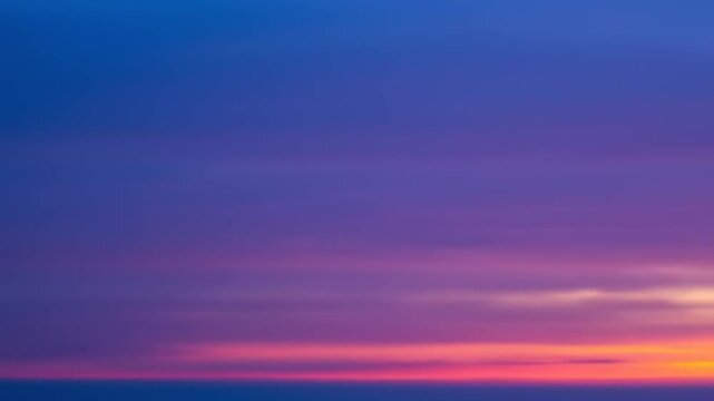 Vibrant sunset with a gradient of colors illuminating the sky over a tranquil horizon at dusk