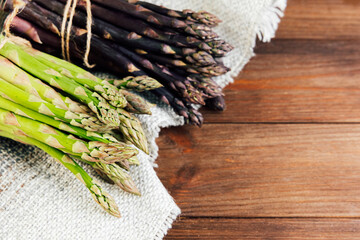 Fresh asparagus varieties on a rustic wooden table with natural fabric
