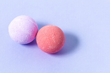 Colorful bath bombs resting on a soft purple surface in a calm and relaxing setting