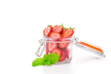 Glass jar filled with fresh sliced strawberries, decorated with mint leaves, on white background. Healthy summer snack, fruit storage, clean eating concept.