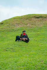 The Asian male traveler sits and relaxes with the charm of clean and beautiful green hills. Concept photo of male tourists doing various poses while enjoying the beauty of green hills.