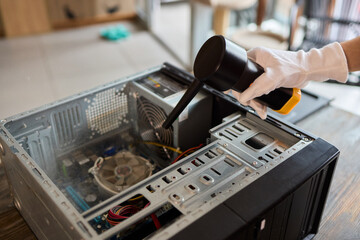 A man cleans a computer case with a vacuum in a bright room, stressing workspace tidiness