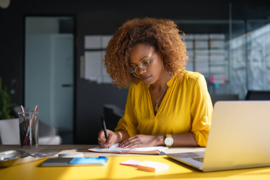 Middle-aged African-American woman scheduling corporate training sessions, reviewing calendar invites and booking meeting rooms with ease