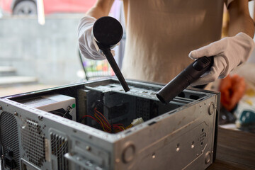 A man cleans a computer case with a vacuum in a bright room, stressing workspace tidiness