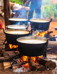 Palm sugar being prepared in cooking pots over an open fire in a rural Cambodian village.