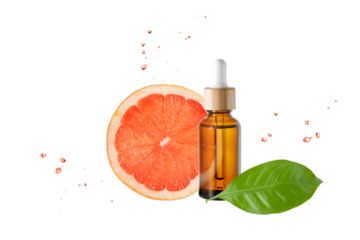 Amber bottle of face serum with vitamin C or essential oil and grapefruit fruit slices and leaves with flying drops isolated on white background.