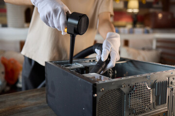 A man cleans a computer case with a vacuum in a bright room, stressing workspace tidiness