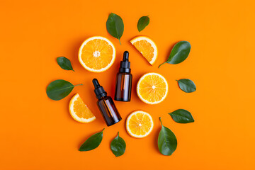 A beautiful composition of orange slices green leaves and essential oil dropper bottles on an orange colored background showcasing natural skincare ingredients