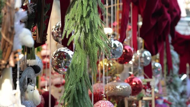 Decorated Christmas tree branch adorned with vibrant ornamental baubles in retail environment, highlighting seasonal festive merchandising display